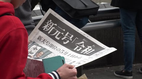 SHIBUYA,  TOKYO,  JAPAN - CIRCA APRIL 1st 2019 : “REIWA” becomes the new name, for a new era, under a new Emperor.  People holding copy of Asahi newspaper reporting the name of new era.
