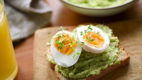 Breakfast toast with egg and avocado on breakfast table. Closeup view. HD footage