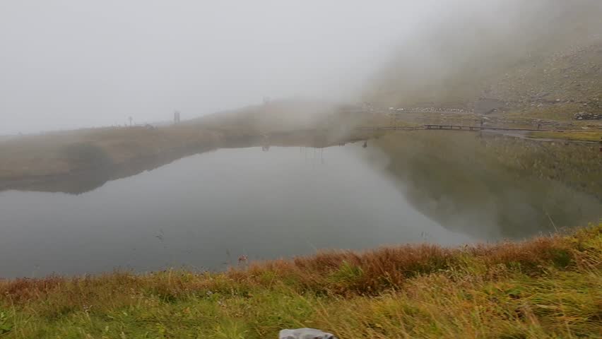 Driving on the Grossglockner Alpine Pass in Austria and passing a foggy lake.