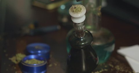 Medical cannabis being lit and smoked through a dirty water bong.
