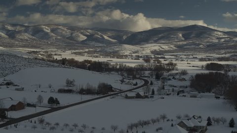 Aerial view of road and houses in valley near mountain range in winter / Wallsburg, Utah, United States