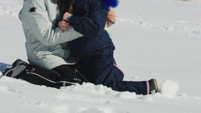 Tilt up to smiling mother and daughter kneeling in snow and hugging / South Fork, Utah, United States