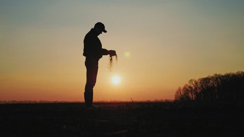 Farmer holding soil in hands at sunset. Male hands touching soil on the field. Farmer is checking soil quality before sowing wheat.