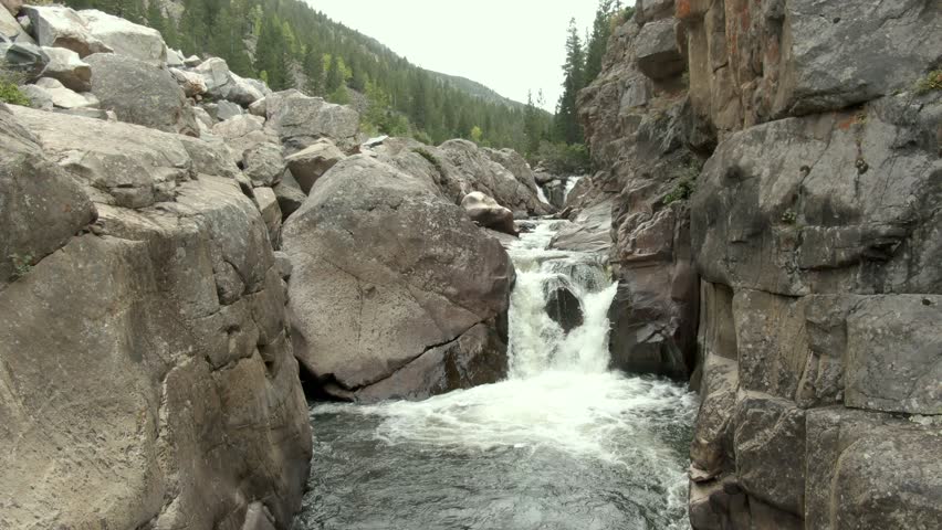 Aerial rising out of canyon with waterfall and river in Colorado