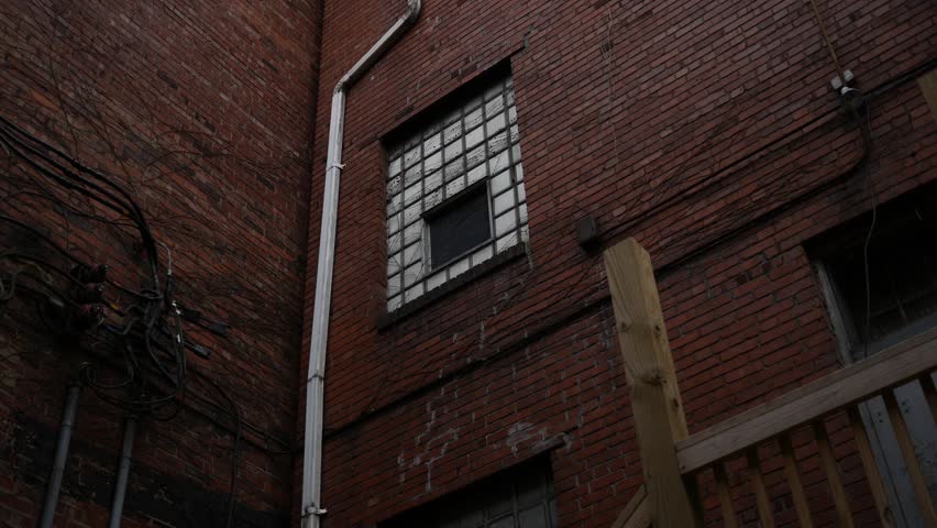 An old window in an abandoned industrial building a seen from alley