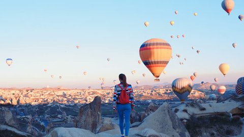 Yoing traveler with backpack looking to the air baloons. sporty girl and a lot of hot air balloons. The feeling of complete freedom, achievement, achievement, happiness