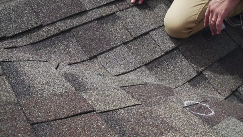 Roof hail damage inspection with chalk circles marking damaged shingles