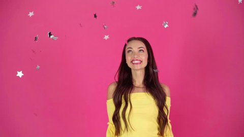 slow motion shoot of happy young woman looking at silver confetti falling down
