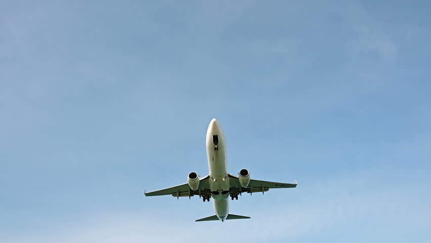 Slow motion of jet plane approaching landing across blue sky | Shutterstock HD Video #1026797882