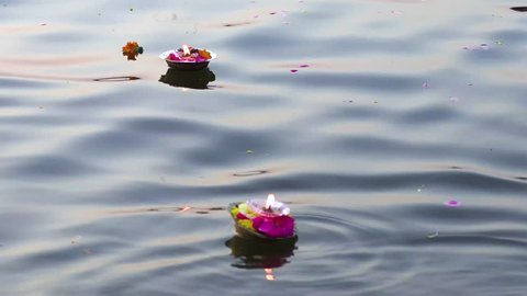 Hinduism religious ceremony puja flowers and candle on the sacred river Ganges water in Varanasi, India, close up, 4k footage video