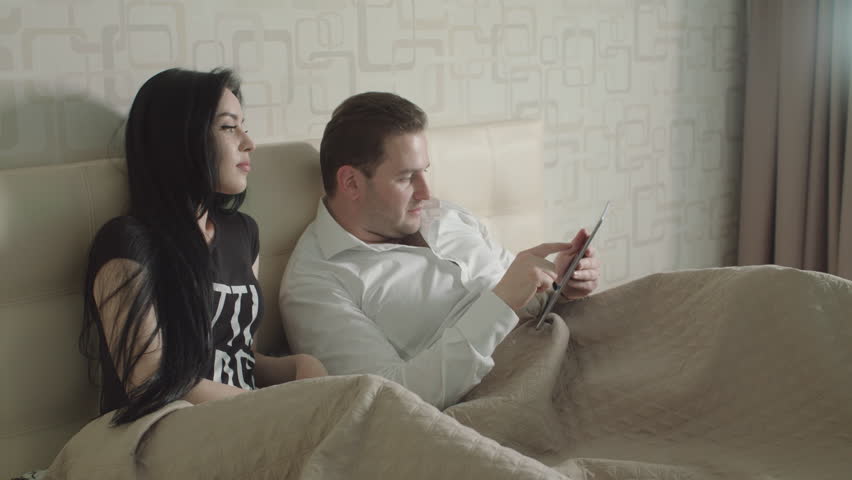 Parents Are Watching TV. They Be In Bed In Bedroom. Night.