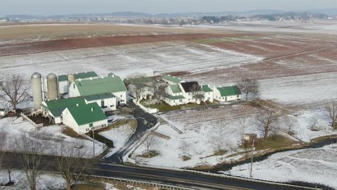 Drone circling farm in snow covered rural town. Shot in Intercourse, Pennsylvania in wintertime. A beautiful snow covered rural town with farms, meadows, farmlands and a small village center.