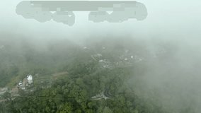 An aerial shot of a bus going through a jungle road which then fades away as the drone flies into a cloud.