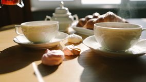Cozy morning moment. tea is poured into cups from french press. Croissants and sweets. Sweet breakfast breakfast. Video footage