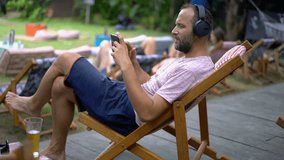 Young, happy man watching movie on smartphone in city park