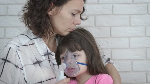 Woman with a sick child. The little girl in the mask nebulizer.