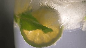 close-up refreshing soda tonic with lime and ice in a glass. Cold lemonade mojito drink. 4K UHD video 3840x2160