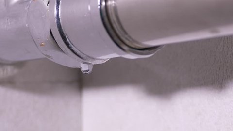 Ungraded: Water leakage. Drops of pure water dripping from a shiny metal pipe of heated towel rail in the bathroom. Ungraded H.264 from camera without re-encoding.