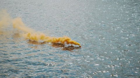 Slow motion of a water smoke bomb distress beacon releasing a stream of smoke during a training exercise in boat emergency survival