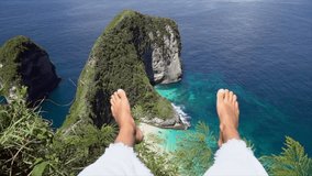 Personal perspective of female legs out on top of idyllic Kelingking beach in Bali Indonesia. People travel pov environment conservation concept. Girl hanging feet above idyllic beach 
