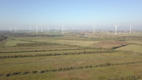 Landscape scenery with offshore windmills farm, filmed from a drone perspective. Windmills are located in nice agriculture area close to Puck city in Poland
