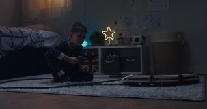 Cute little kid boy playing with radio controlled train in his room, evening shot. 4K UHD RAW FOOTAGE
