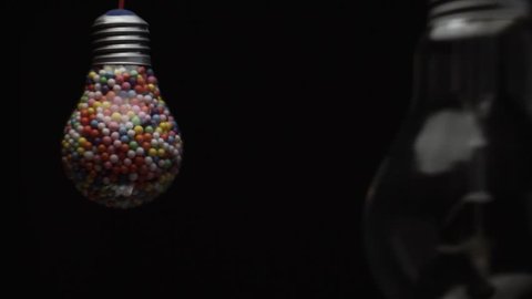 Lightbulb filled with colored ball black background. 