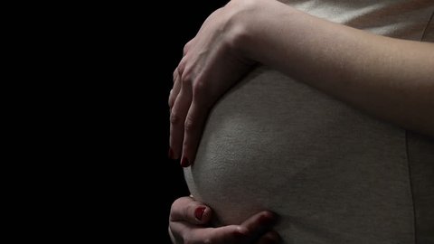 Pregnant woman stroking belly isolated on black, health risks during pregnancy