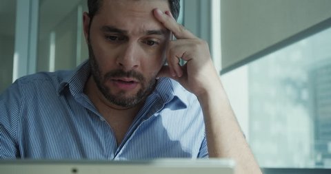 Angry businessman working with laptop computer in office, losing patience. Impatient business man under stress at work with pc. Young latin manager worried for technology problems and software virus