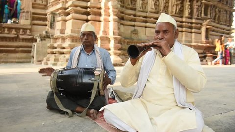 KHAJURAHO, MADHYA PRADESH, INDIA 10 OCTOBER 2018 : Unidentified senior artist playing Shehnai folk music of India in front of Jain temple in morning at Khajuraho, India.