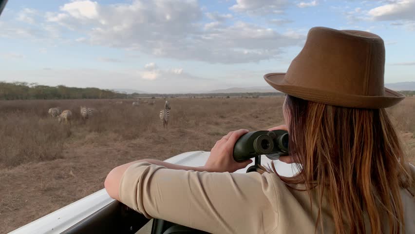 Woman on a safari trip in Masai Mara spotting zebras