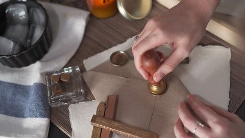 Stamping Gold Wax Seal onto a Brown Envelope