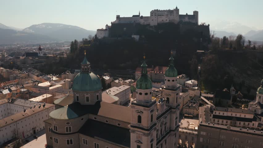 Flying over the historic city of Salzburg with Salzach river, Salzburger Land, Austria. Aerial panoramic view with Alps on the background.