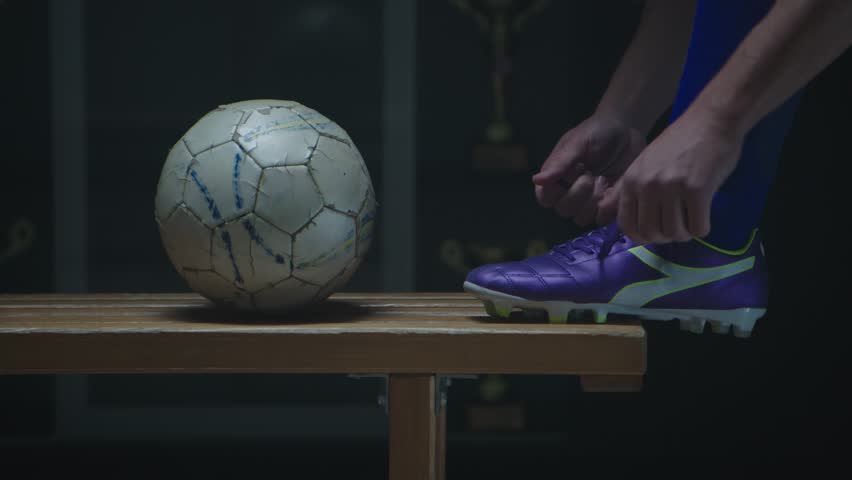 Soccer player tying his football boots in locker room - Powered by Shutterstock - Get 15% off with code: PIKWIZARD15