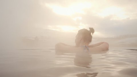 Back view of beautiful naked woman bathing and relaxing in Hot Springs. Peace and quiet