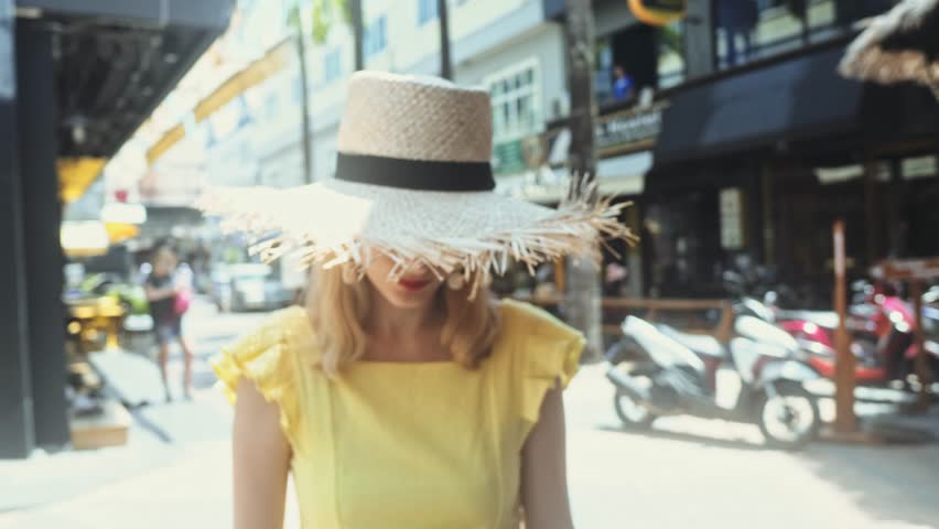 Young Beautiful woman in straw hat walk straight to the camera and smiles