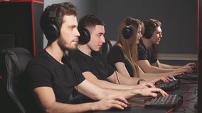 Group of concentrated people in headphones enjoying online video game on powerful computers of gaming centre.