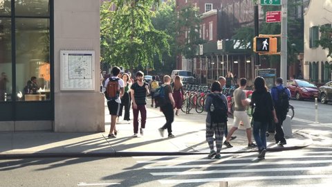 NEW YORK CITY - JUNE 20, 2018: NYU students busy intersection crosswalk 8th street University Place people crowded summer NYC 4K and 1080 HD. Greenwich Village serves as the unofficial campus for NYU.