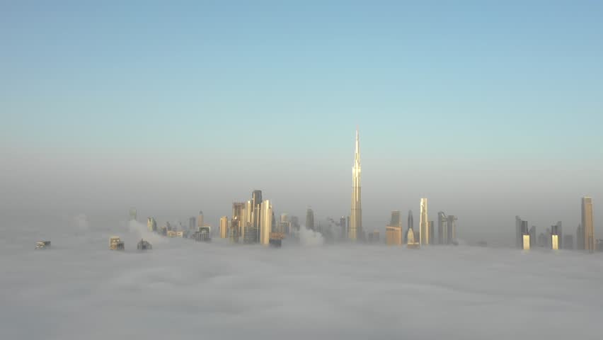 Aerial view of Dubai Downtown skyline being covered in winter morning fog - drone flying away from the cityscape and descending into the fog. Dubai, UAE. | Shutterstock HD Video #1026875177