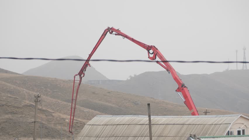 concrete pump on the roof of the house on the background of the hills