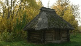 Tiny. log cabin outbuilding with traditional thatched roof. standing on a rural farm in Ukraine. 6k video