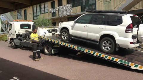 MELBOURNE - APRIL 2019: Truck driver of breakdown support and towing service truck towing a Toyota Land Cruiser Prado vehicle. Every year about 1.2 million cars broken down in Australia.