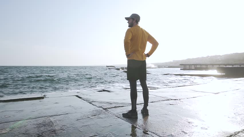 Young male runner training outdoors on the beach during sunset 