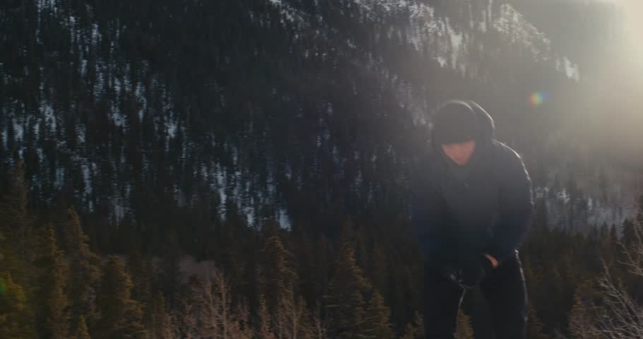 Young Man Throws Snowball with Mountains and Sunset in the Background