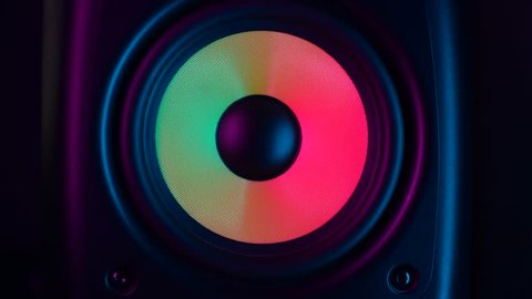 Close up of colorful loud bass speaker vibration on black background