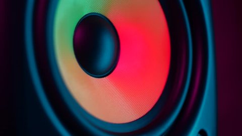 Close up of colorful loud bass speaker vibration on black background