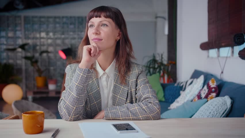 Pensive young business elegant woman texting on smart phone device in cozy loft, getting genial idea, entrepreneur goals, making a gesture, hard worker, using online messenger application, ceramic