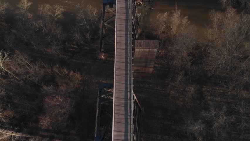 Flying directly over High Bridge Trail, a reconstructed Civil War railroad bridge in Virginia, looking down to see the Appomattox River pass beneath the bridge. UHD aerial footage.