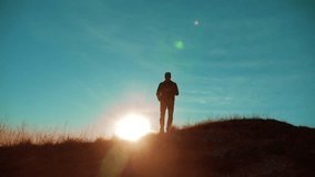 Male man worth it tourist with backpack on the top of the mountain. smartphone navigation. sunlight stands on top of a mountain. slow motion video. man silhouette at sunset . hikers adventure and