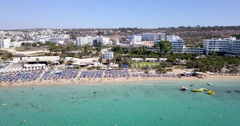Aerial view of a holiday resort sandy beach, with beach umbrellas and sun beds. Crowded sandy beach in Ayia Napa Cyprus.
